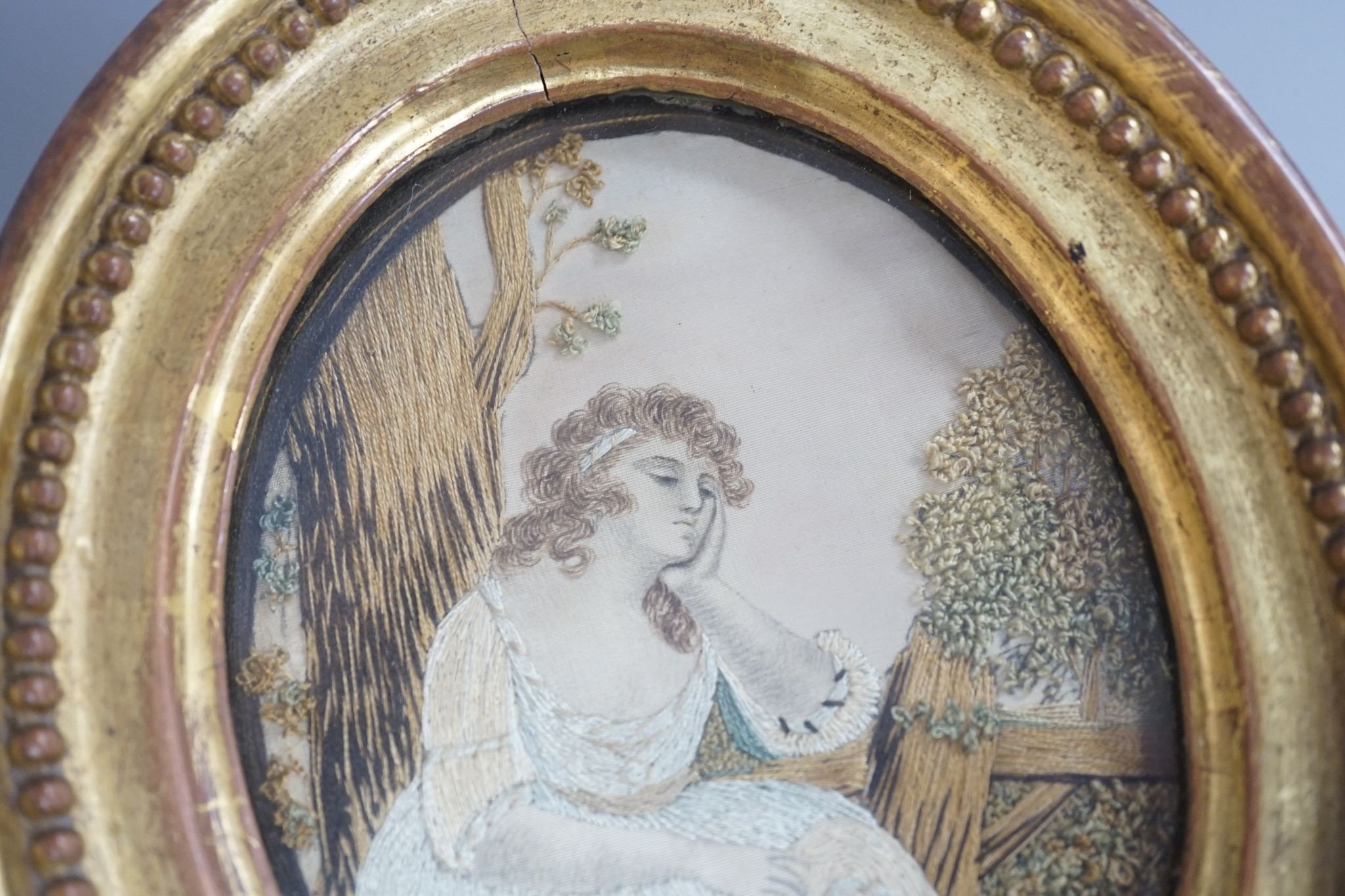 An oval gilt framed Regency silkwork of a seated girl 11x9cm